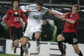 Edin Džeko z Wolfsburgu se probíjí mezi hráči Manchesteru.