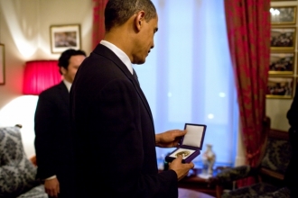 Obama si prohlíží medaili s Nobelem.