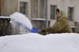 Žena v Jablonci nad Nisou odklízí nový sníh.