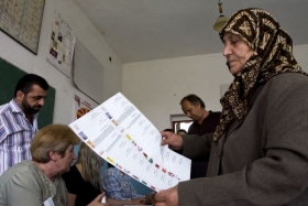 Etnická Albánka se soupisem stran ve volební místnosti.