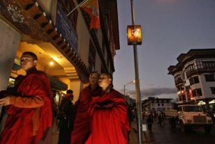 Mniši a svítící portrét nového krále Bhútánu na trhu v Thimpu.