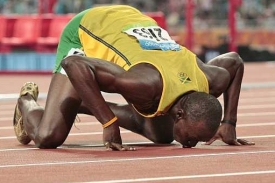 Jamajský běžec Usain Bolt líbá dráhu, na níž pokořil světové rekordy.