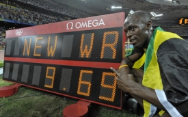 Usain Bolt a vedle něj na tabuli hodnota jeho nového světového rekordu.