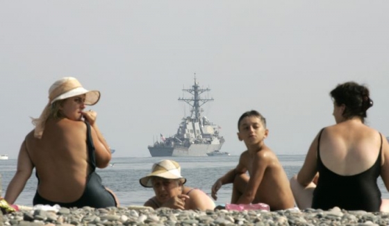 Obyvatelé Batumi se sluní na břehu moře. V pozadí loď McFaul.
