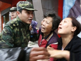 Voják se snaží udržet dál od trosek školy zoufalé příbuzné obětí.
