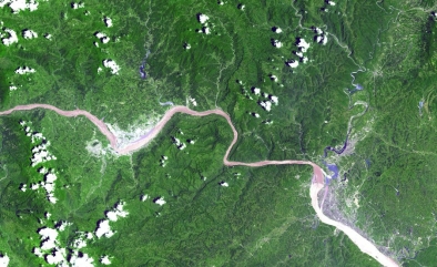 Dlouhá řeka s budovanou přehradou při pohledu z vesmíru.