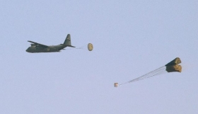 C-130 Hercules shazuje zásoby zbraní a munice.