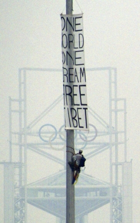 Demonstrant vyvěšuje transparent na podporu svobodného Tibetu.