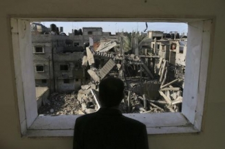 Palestinec se dívá ze svého bytu na rozbombardované okolí.