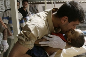 Iráčan líbá mrtvolku svého dvouletého syna, zabitého při výbuchu.