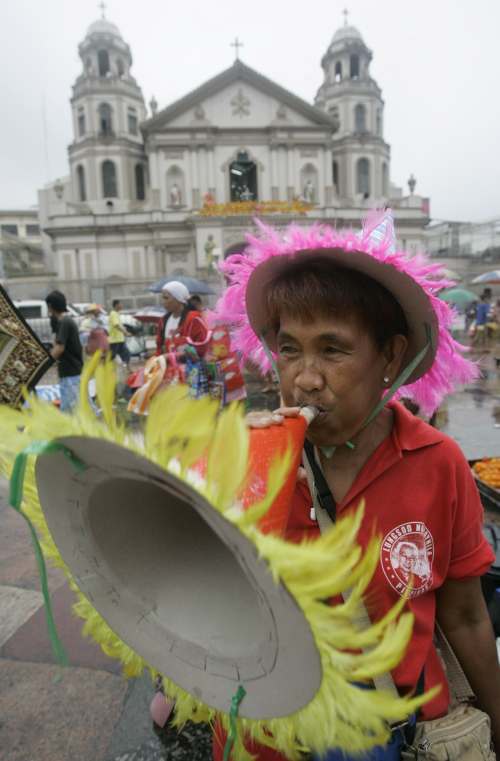 Filipínský obchodník troubí na papírovou trubku a láká nakupující.