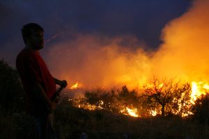 Muž hasí požár u řecké vesnice