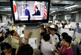 Tiskové středisko v Tójaku. Na obrazovce Bush a Fukuda.