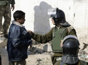 Člen pořákové policie zahání mladého Palestince zpět do Gazy