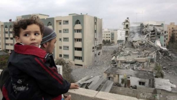 Muž s dítětem se dívá na zničenou budovu Islámské univerzity.