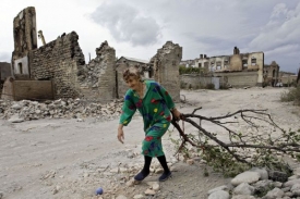 Žena sbírá otop ve zničeném Cchinvali v Jižní Osetii.