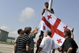 Gruzínští oficíři v civilu vyvěšují gruzínskou vlajku v Gori.