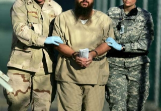 Vězeň se strážnými na Guantánamu.