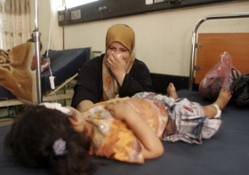Irácká matka pláče u nemocničního lůžka své dcery, zraněné bombou.