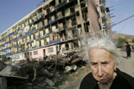 Gruzínská žena stojí před svým zničeným domem.