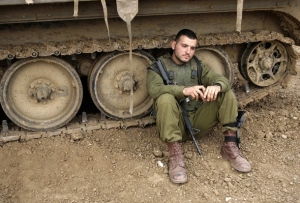 Izraelský voják čeká, až na něj přijde řada překročit hranice Gazy.