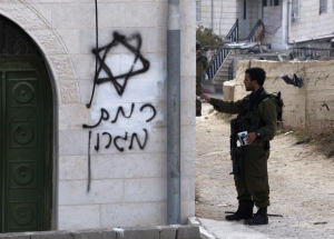Voják odstraňuje graffiti, která na mešitu nastříkali osadníci.