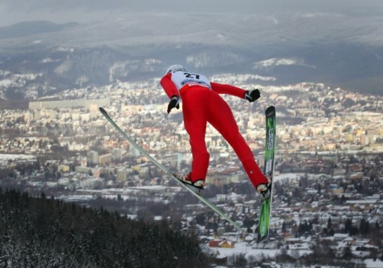 Pohled na skokana na lyžích a město Liberec krátce po odrazu z můstku.