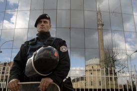 Policejní stráž před budovou kosovského parlamentu s odleskem mešity