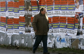 Muž prochází kolem zdi s volebními plakáty.