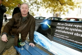 Jiří Lábus pózuje před vládním plakátem, který před chvílí vylepil