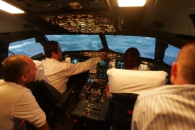Noví piloti se zaučují na leteckém trenažéru.