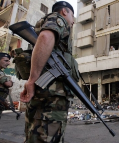 Libanonský voják střeží obhlíží bejrútský obchod, zničený explozí.