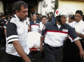 Pracovníci červeného kříže vynášejí mrtvá těl ven z klubu News Divine.