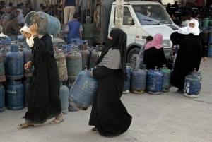 Palestinské ženy si odnášejí plynové bomby z čerpací stanice v Gaze.