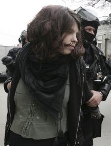 Policie odvádí zadrženou dívku protestující proti summitu NATO.