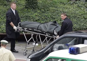 Zaměstnanci pohřební služby odvážejí mrtvé z místa činu