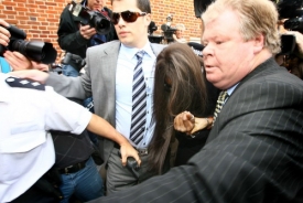 Naomi Cambellová v doprovodu advokáta se snaží skrýt před novináři.