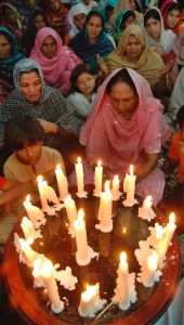 Lidé zapalují svíčky za zesnulé při útku na dav vítající Bhuttovou