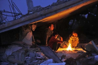 Obyvatelé Džabalíje v Gaze se hřejí u ohně ve svém zničeném domově.