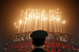 Člen čínské policie sleduje ohňostroj při zahájení paralympiády.