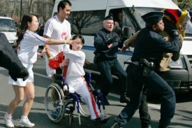 Paralympička brání pochodeň před demonstranty.