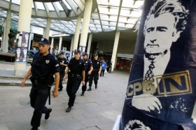 Bělehradští policisté míjejí na hlídce plakát Karadžiče.