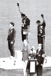 Dvojice afro-amerických sprinterů Tommy Smithe a John Carlos zdvihají na OH v Mexiku 1968 pěst oblečenou v černé rukavici na znamení solidarity s utlačovanými černochy. Za tento tichý protest během předávání medailí za běh na 200 metrů byli vyloučeni z olympijské vesnice a museli neprodleně opustit zemi.