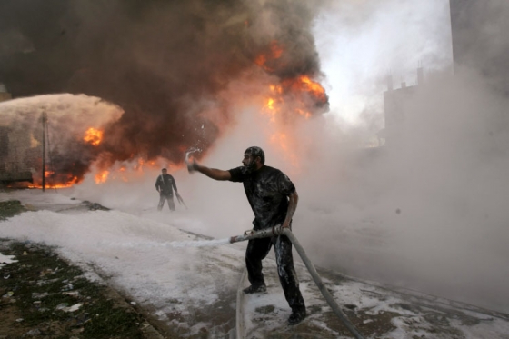 Hašení hořících trosek po náletu v Rafáhu.