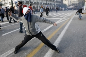 Demonstrující mladík hází kámen na policisty před parlamentem.