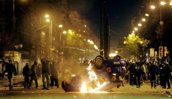 Mladíci bojující s policií u zapáleného auta v ulicích Atén.