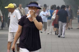 Žena prochází ulicí Pekingu, který přikryl hustý smog.