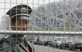 Čínský policista střeží pekingský olympijský stadion.