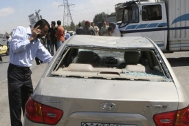 Muž prohlíží své auto poškozené explozí v Damašku.