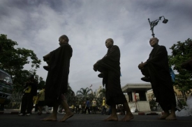 Mniši kráčejí před zčásti obsazeným úřadem vlády.